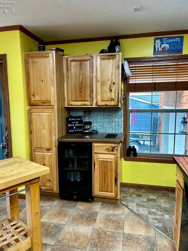 kitchen featuring decorative backsplash, ornamental molding, a textured ceiling, light tile patterned flooring, and beverage cooler