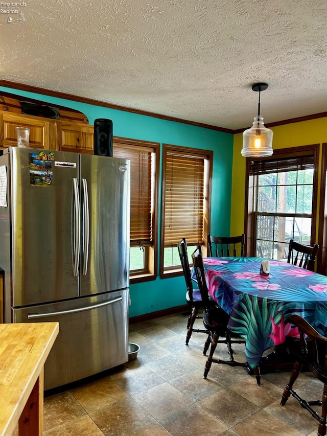 kitchen with tile patterned flooring, ornamental molding, decorative light fixtures, a textured ceiling, and stainless steel fridge