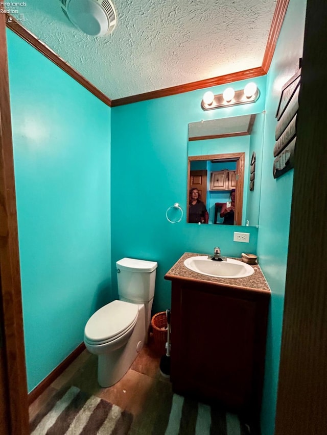 half bath with toilet, a textured ceiling, crown molding, and vanity