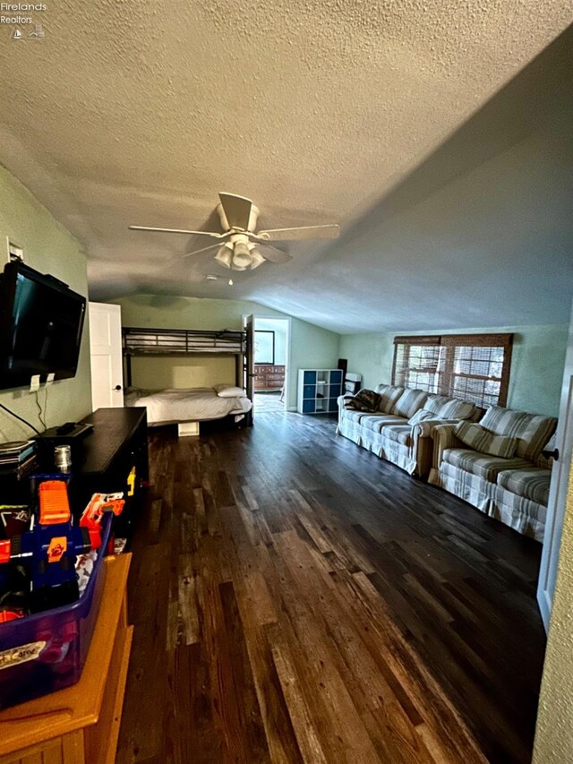 interior space featuring ceiling fan, wood-type flooring, a textured ceiling, and lofted ceiling