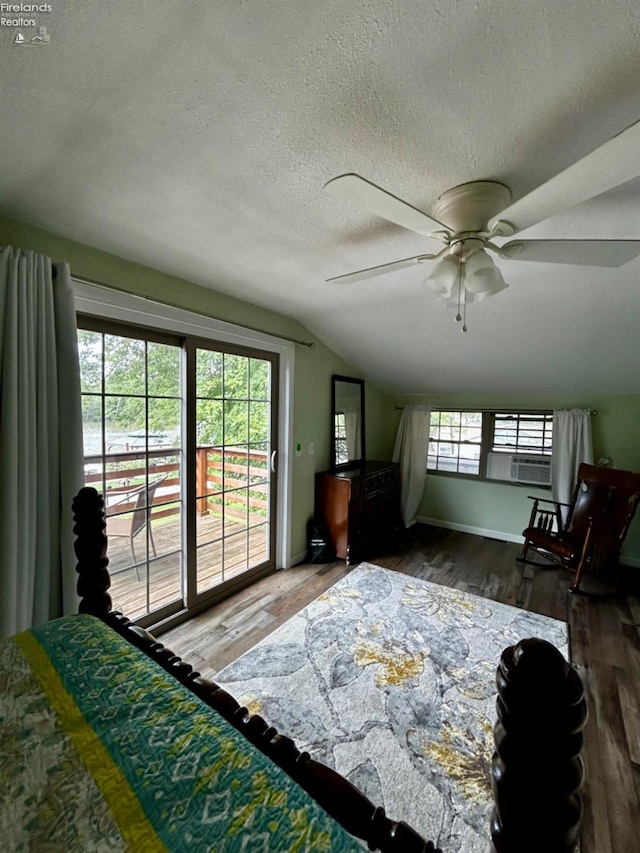 bedroom featuring access to outside, vaulted ceiling, a textured ceiling, and wood finished floors