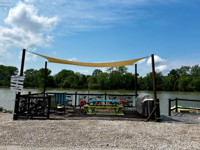 view of dock with a water view and a wooded view