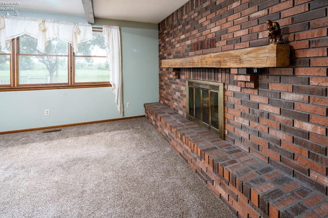 unfurnished living room featuring brick wall, beam ceiling, carpet, and a brick fireplace