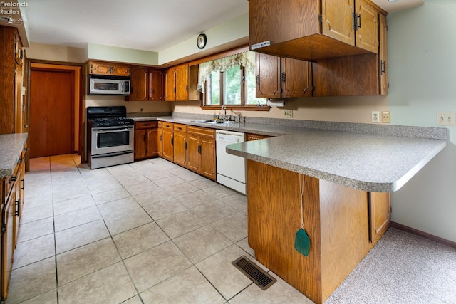 kitchen with light tile patterned floors, stainless steel appliances, sink, and kitchen peninsula