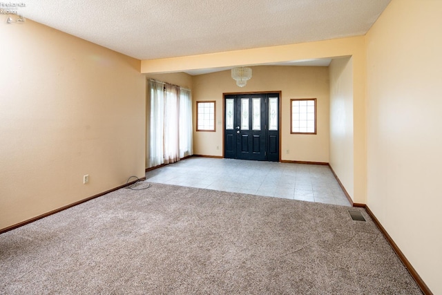 foyer featuring light colored carpet and a textured ceiling