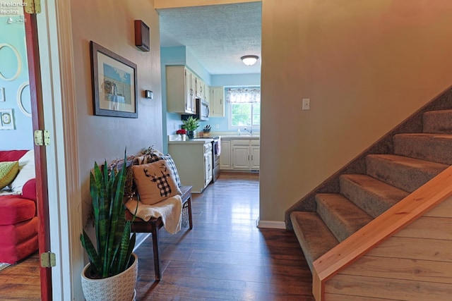 hallway featuring sink, a textured ceiling, and dark hardwood / wood-style floors