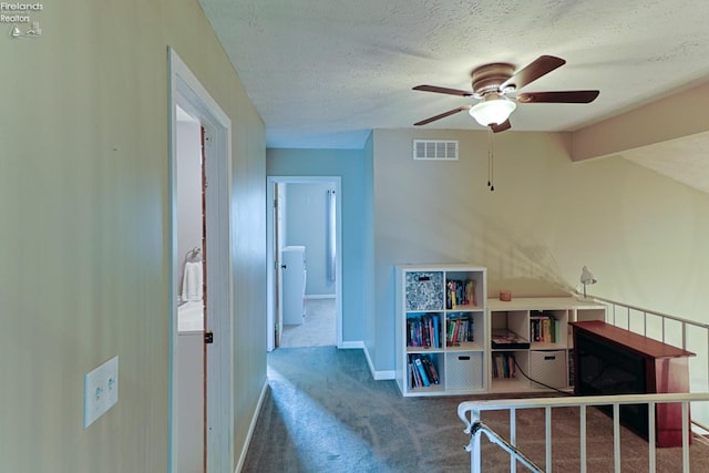 corridor featuring carpet, beam ceiling, and a textured ceiling