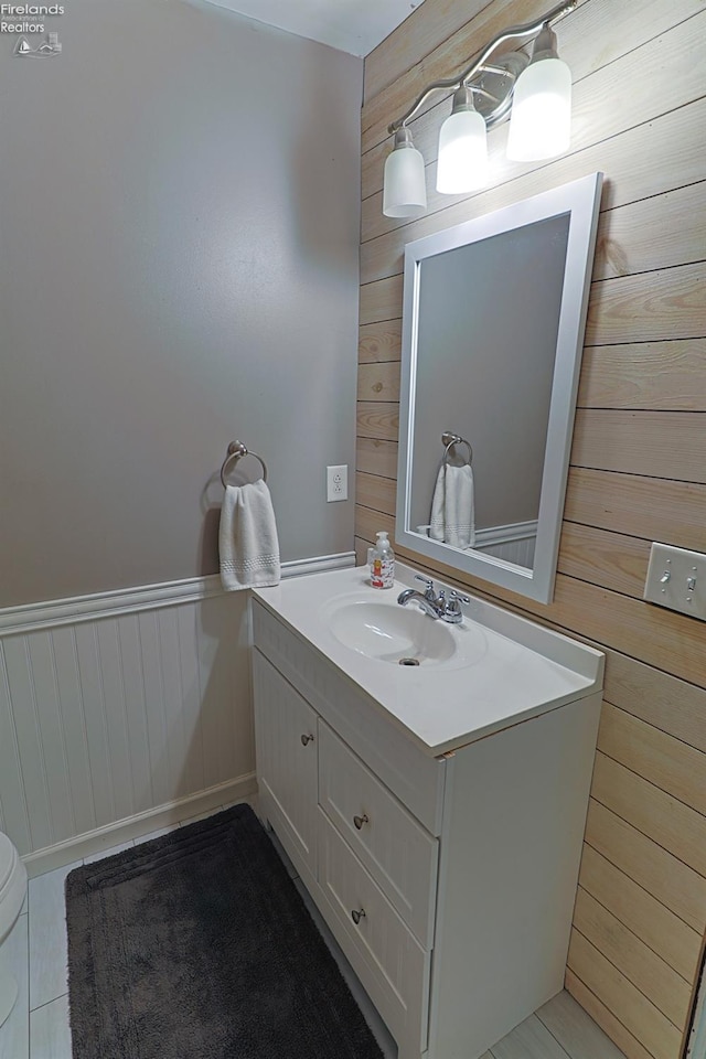 bathroom featuring vanity, tile patterned floors, toilet, and wooden walls