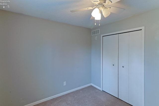 unfurnished bedroom with carpet floors, ceiling fan, and a closet