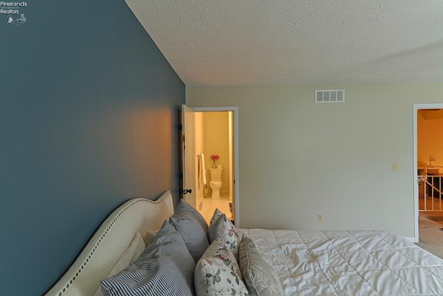 bedroom with ensuite bath and a textured ceiling