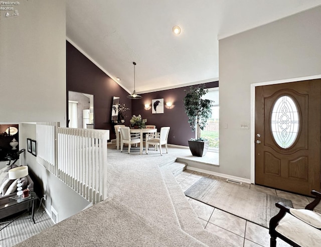 foyer with lofted ceiling, plenty of natural light, and light colored carpet