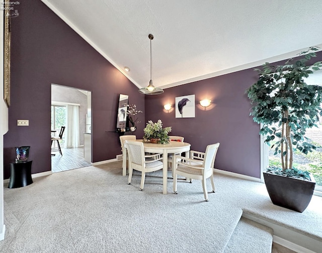 dining area with high vaulted ceiling, a textured ceiling, and light colored carpet