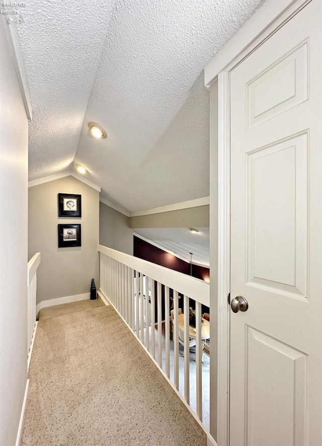 hallway with a textured ceiling, lofted ceiling, and carpet floors