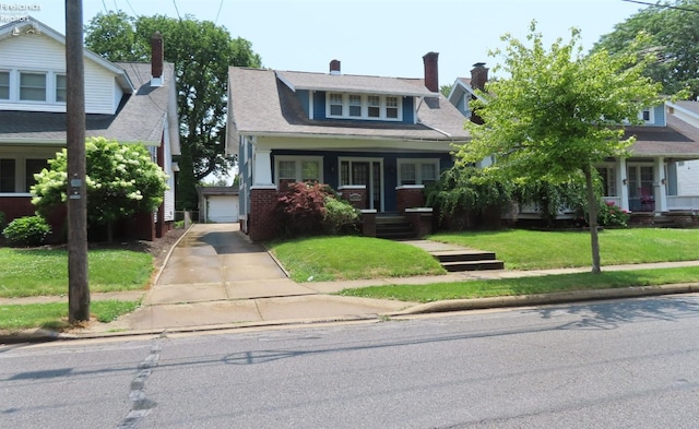 view of front of home featuring an outdoor structure, covered porch, a front yard, and a garage