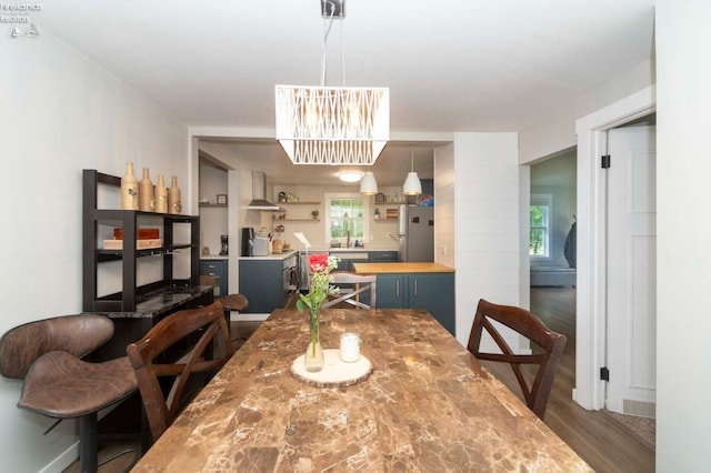 dining space with a chandelier, plenty of natural light, and dark hardwood / wood-style flooring