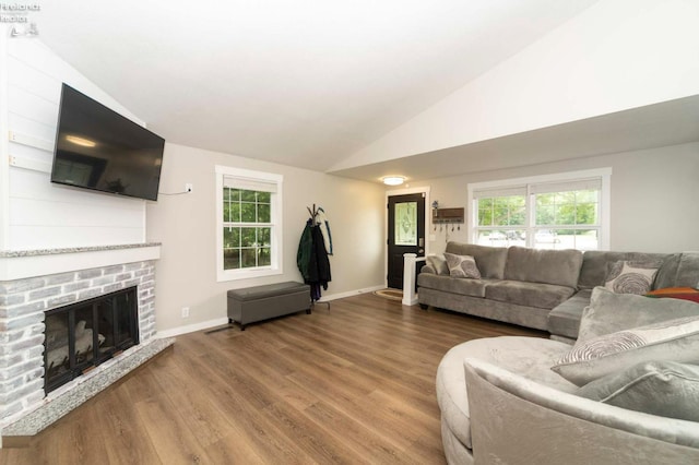 living room with high vaulted ceiling, a brick fireplace, and hardwood / wood-style flooring