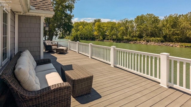 deck featuring a water view, an outdoor living space with a fire pit, and a lawn