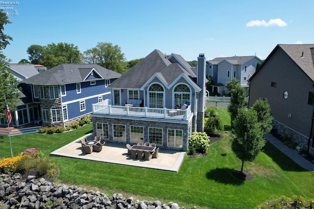 rear view of house featuring a yard, a patio, and a balcony