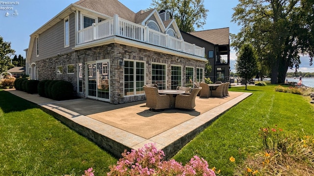 back of property with a balcony, a yard, and a patio area