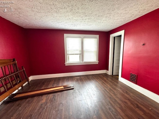 unfurnished bedroom featuring baseboards, a textured ceiling, visible vents, and hardwood / wood-style floors