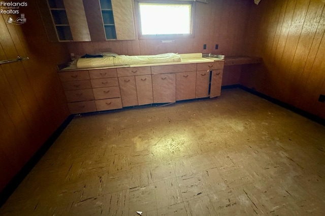 kitchen featuring light countertops, wood walls, and light floors