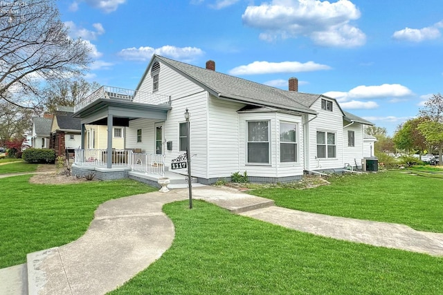 back of property with central air condition unit, covered porch, and a lawn