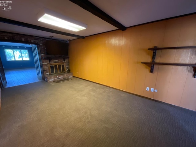 basement featuring wood walls, carpet flooring, and a brick fireplace