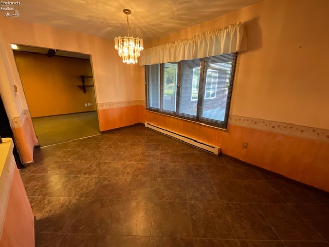 unfurnished dining area with dark tile patterned floors, baseboard heating, and an inviting chandelier