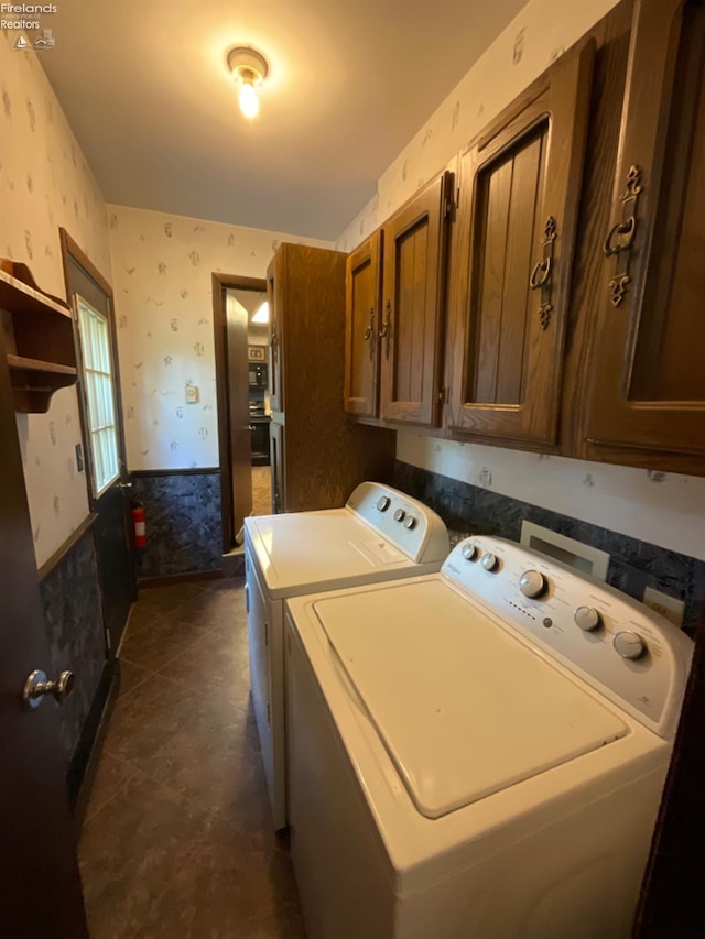 washroom with washing machine and dryer, cabinets, and dark tile patterned flooring