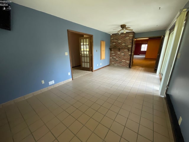 unfurnished living room featuring ceiling fan, light tile patterned flooring, and brick wall