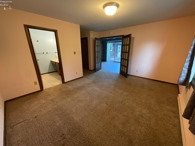 unfurnished bedroom with light carpet and connected bathroom