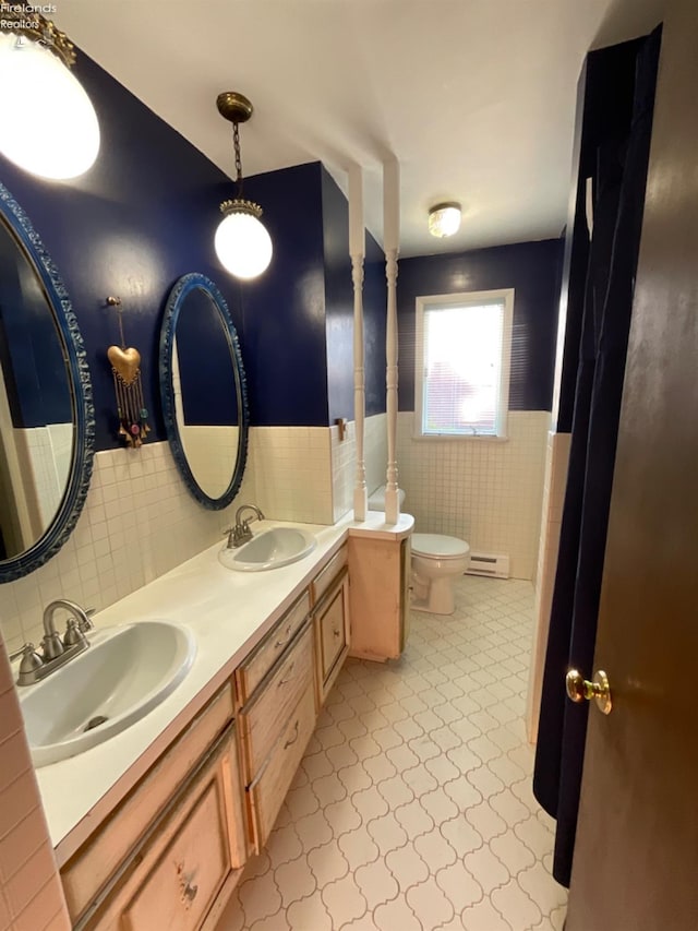 bathroom with tile walls, toilet, vanity, and tile patterned floors