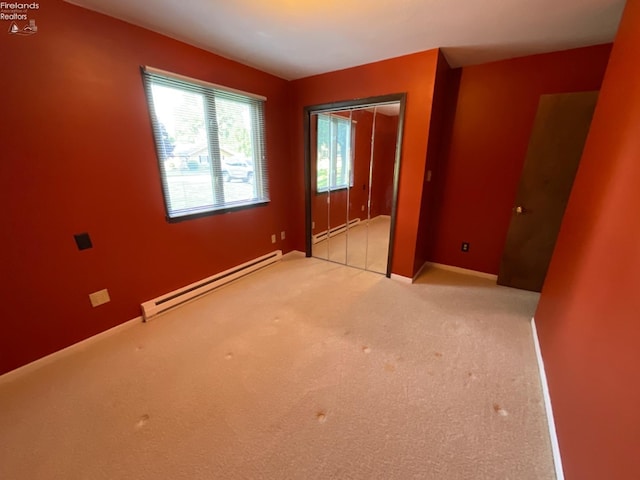 unfurnished bedroom with a closet, a baseboard heating unit, and light carpet