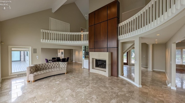 unfurnished living room featuring high vaulted ceiling, light tile patterned floors, and beam ceiling