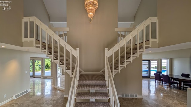 stairs featuring tile patterned flooring, a healthy amount of sunlight, and a towering ceiling