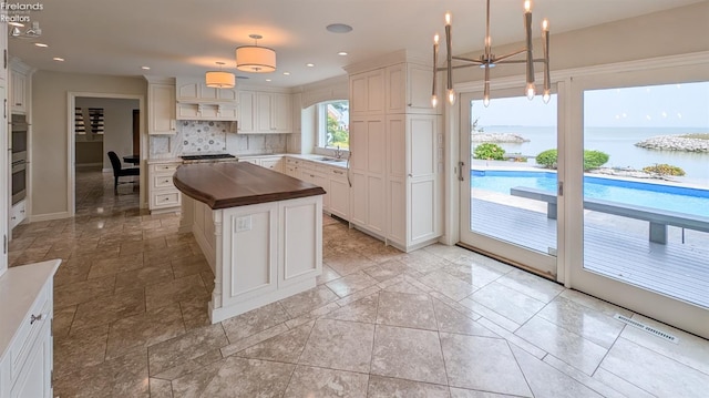 kitchen with butcher block countertops, light tile patterned floors, a kitchen island, and tasteful backsplash