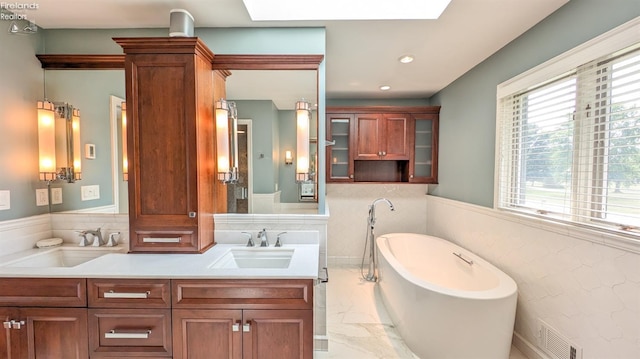 bathroom featuring tile patterned floors, a skylight, a washtub, and vanity