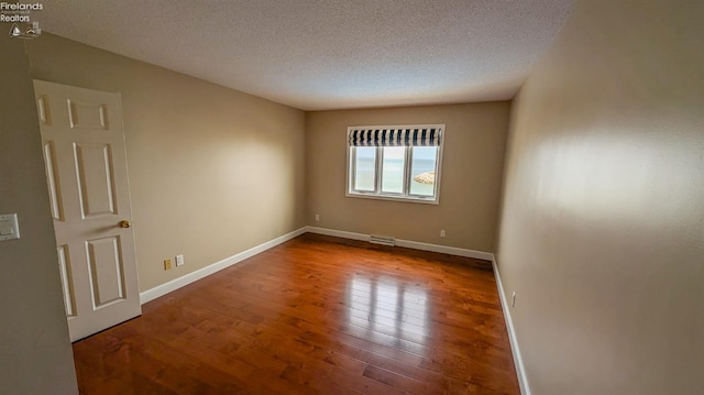 unfurnished room featuring wood-type flooring and a textured ceiling