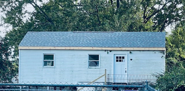 exterior space featuring fence and a shingled roof