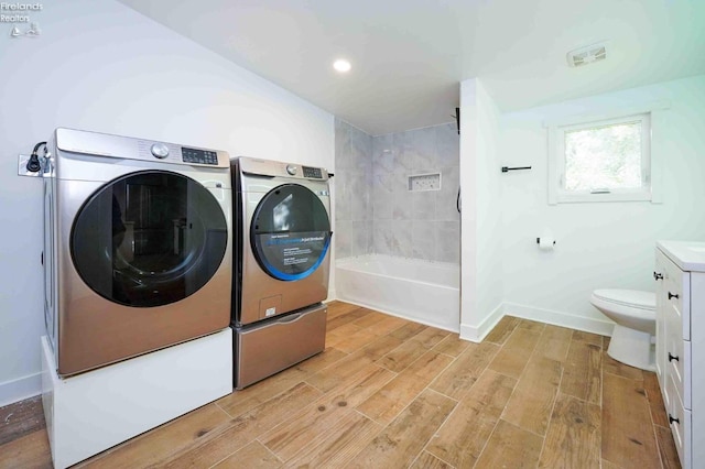 clothes washing area featuring independent washer and dryer and light hardwood / wood-style flooring