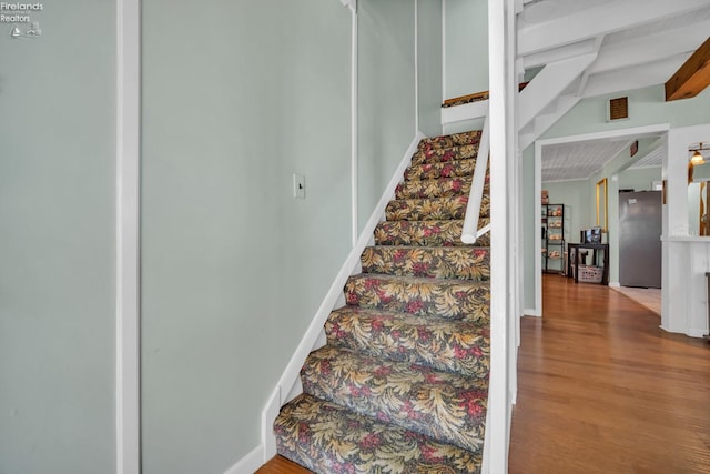 stairway with beamed ceiling and wood-type flooring