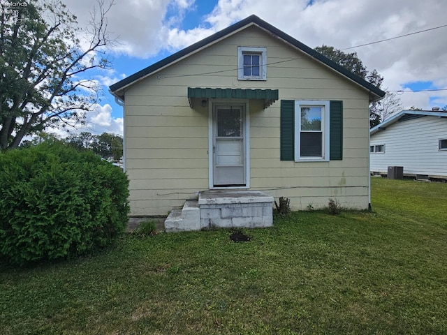 back of house with cooling unit and a lawn