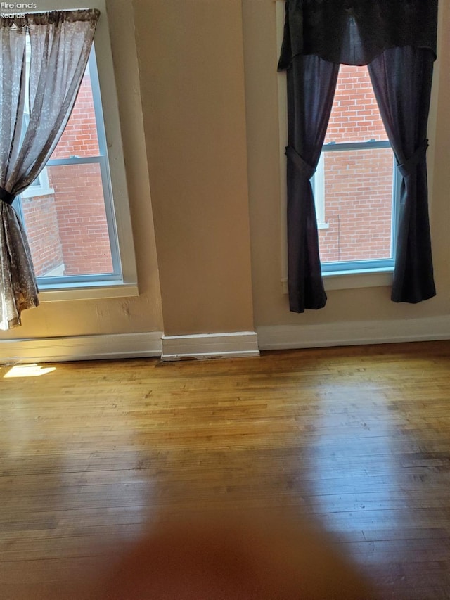 unfurnished room with a healthy amount of sunlight and wood-type flooring