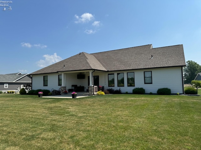 rear view of house with a yard, a shingled roof, and a patio