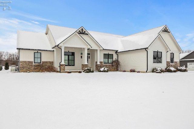 modern farmhouse featuring a detached garage, board and batten siding, and stone siding