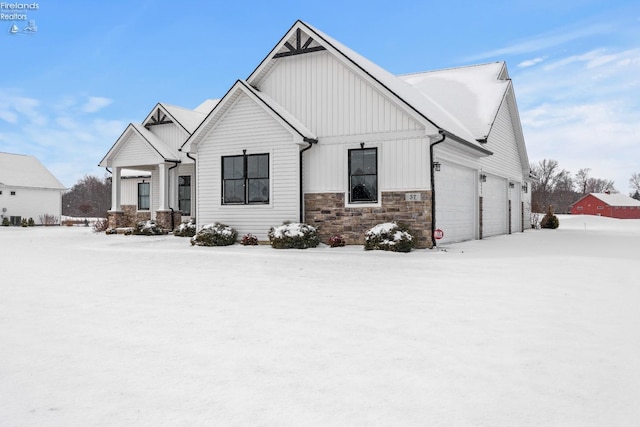 modern farmhouse featuring stone siding, board and batten siding, and an attached garage