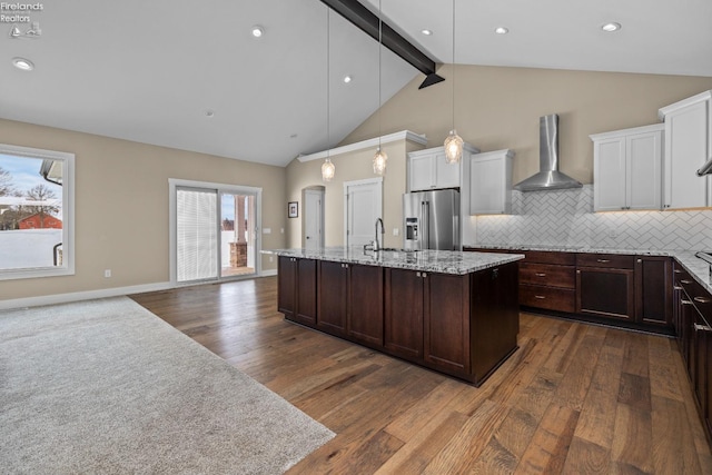 kitchen featuring backsplash, white cabinetry, high quality fridge, dark brown cabinetry, and wall chimney exhaust hood