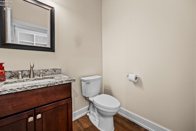 bathroom featuring vanity, toilet, wood finished floors, and baseboards