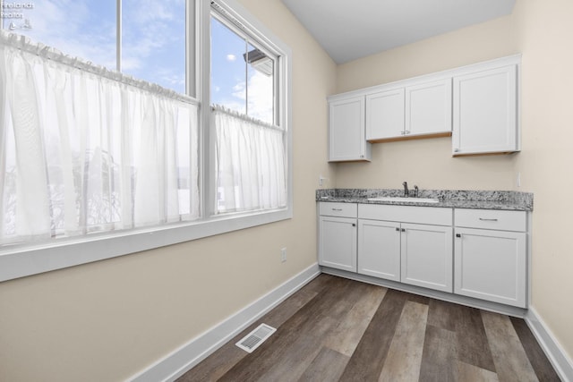 kitchen with visible vents, baseboards, dark wood-style floors, white cabinets, and a sink