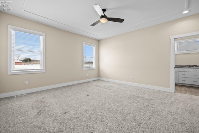 unfurnished bedroom with attic access, a ceiling fan, baseboards, and light carpet